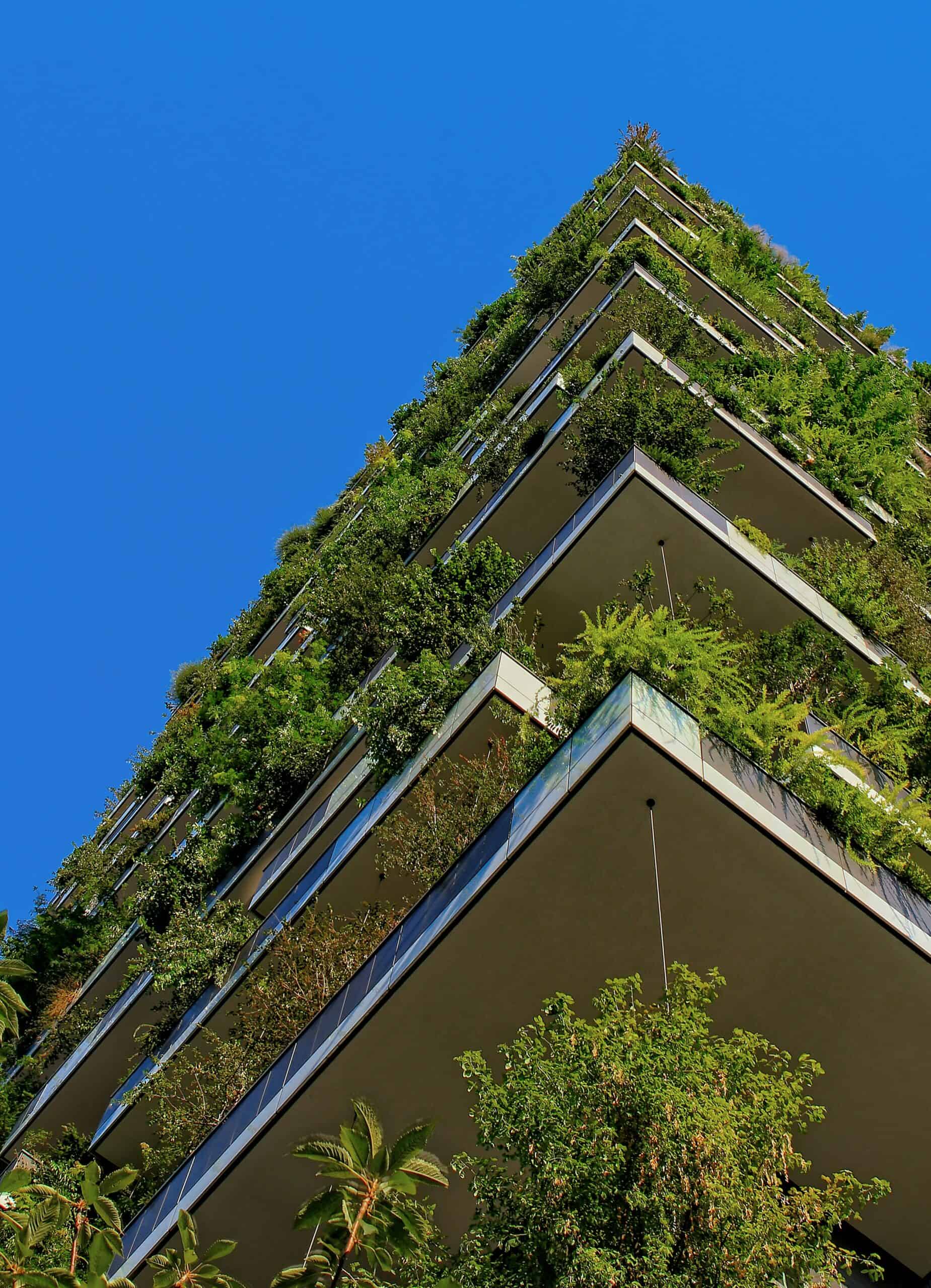 photo of a multiple story building with greet plants growing at every level. There is a blue sky above